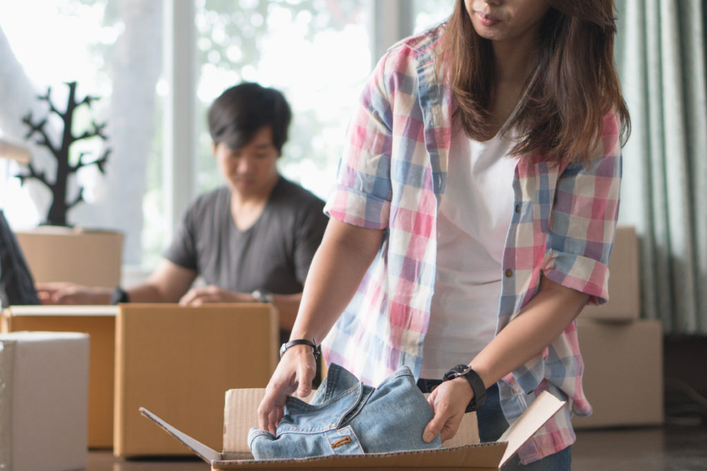Concept young couple moving house. Asian young couple unpack cardboard box after moving in new house.
